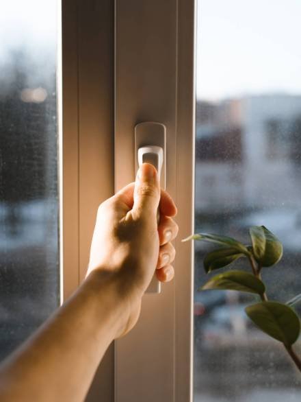 Male hand holding the handle of the window. Man opening (closing) a window. Sun glare on the hand. Vertical photo Ventanas realizadas por Vencor aluminios